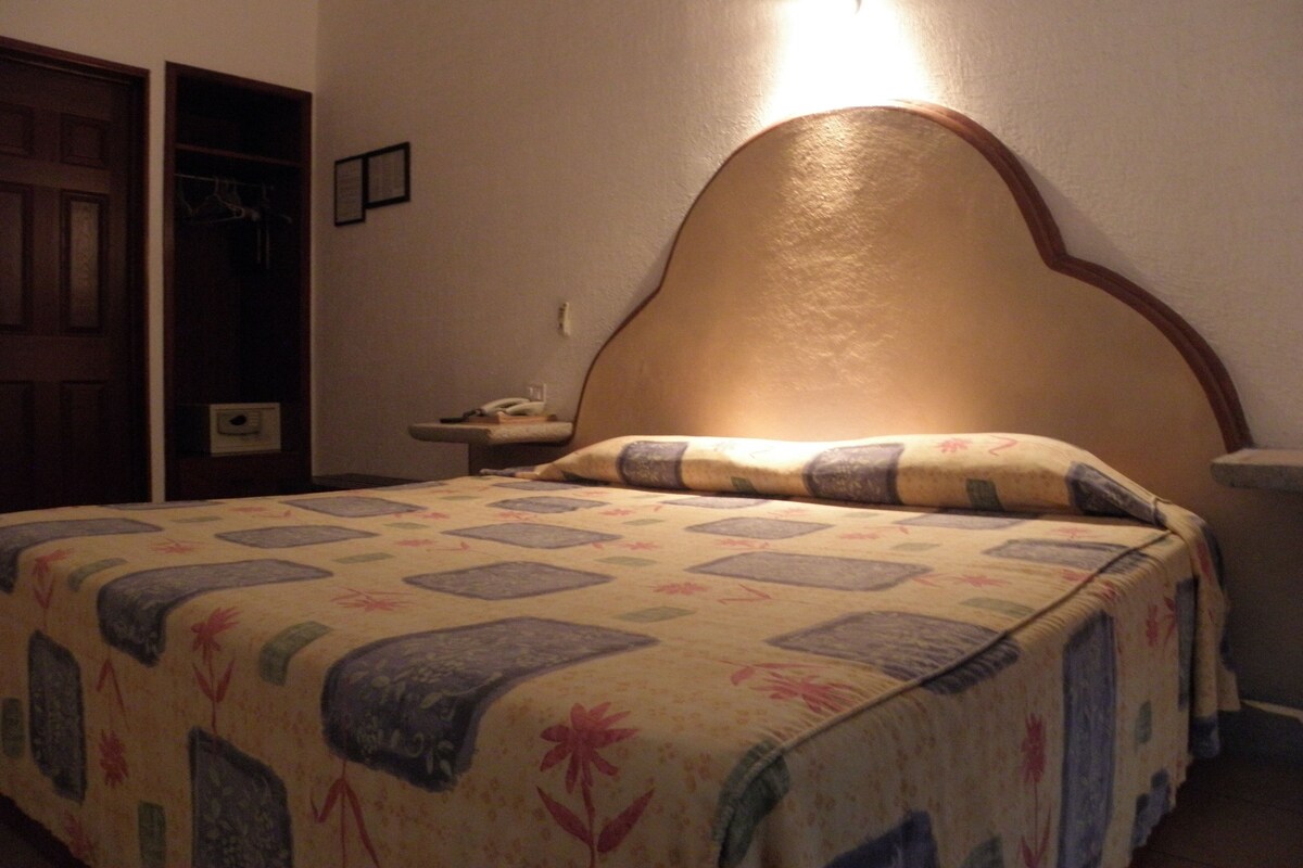 Une chambre à coucher avec un lit, une table de chevet, une tête de lit en bois et une porte.