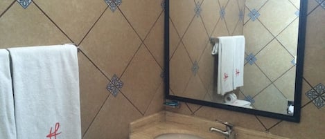 Un baño con lavamanos, espejo y dos toallas.
