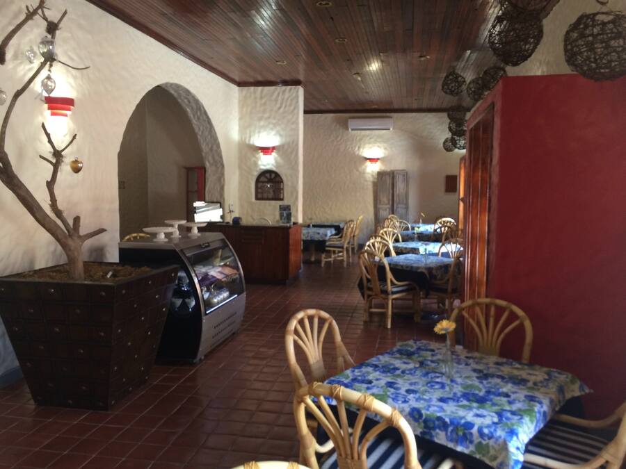 Un restaurante con sillas de madera, un bufé y un árbol decorativo.
