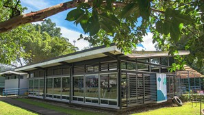 Un edificio moderno con amplios ventanales, un espacio exterior cubierto y un césped.