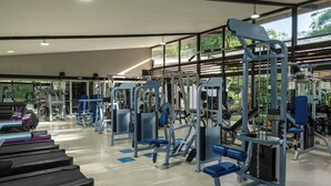 Un gimnasio con cintas de correr, máquinas de pesas y pesas libres.