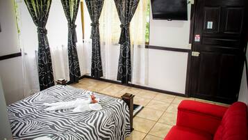 A hotel room with a zebra-patterned bed, a red sofa, and curtains with a black and white design.