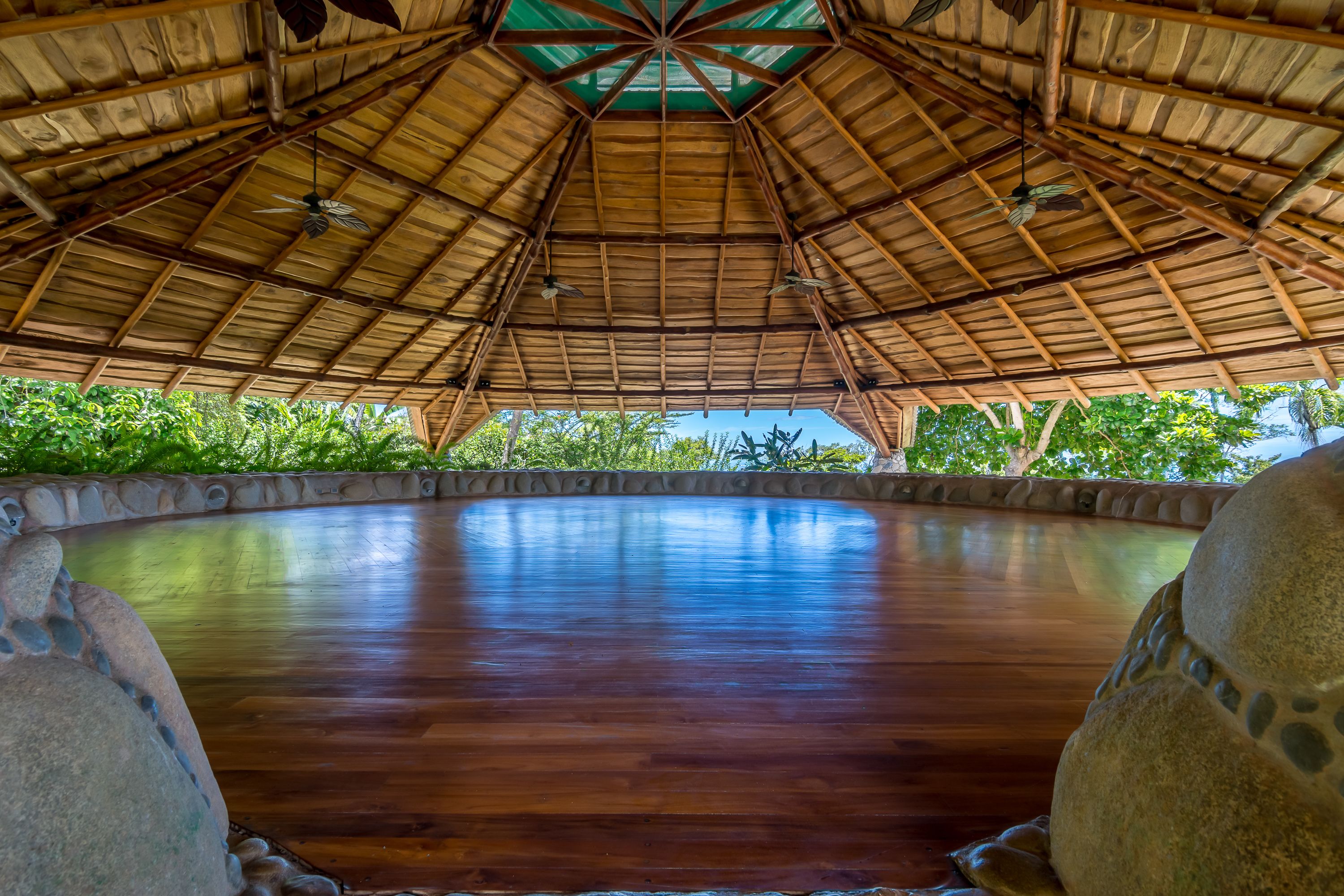 A large, circular wooden pool with a thatched roof overhead.