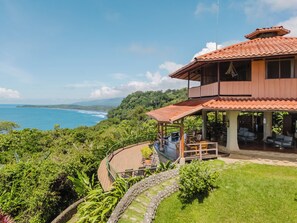 A two-story building with a terrace overlooking a coastal landscape. - La Cusinga Lodge (Bahía Ballena)