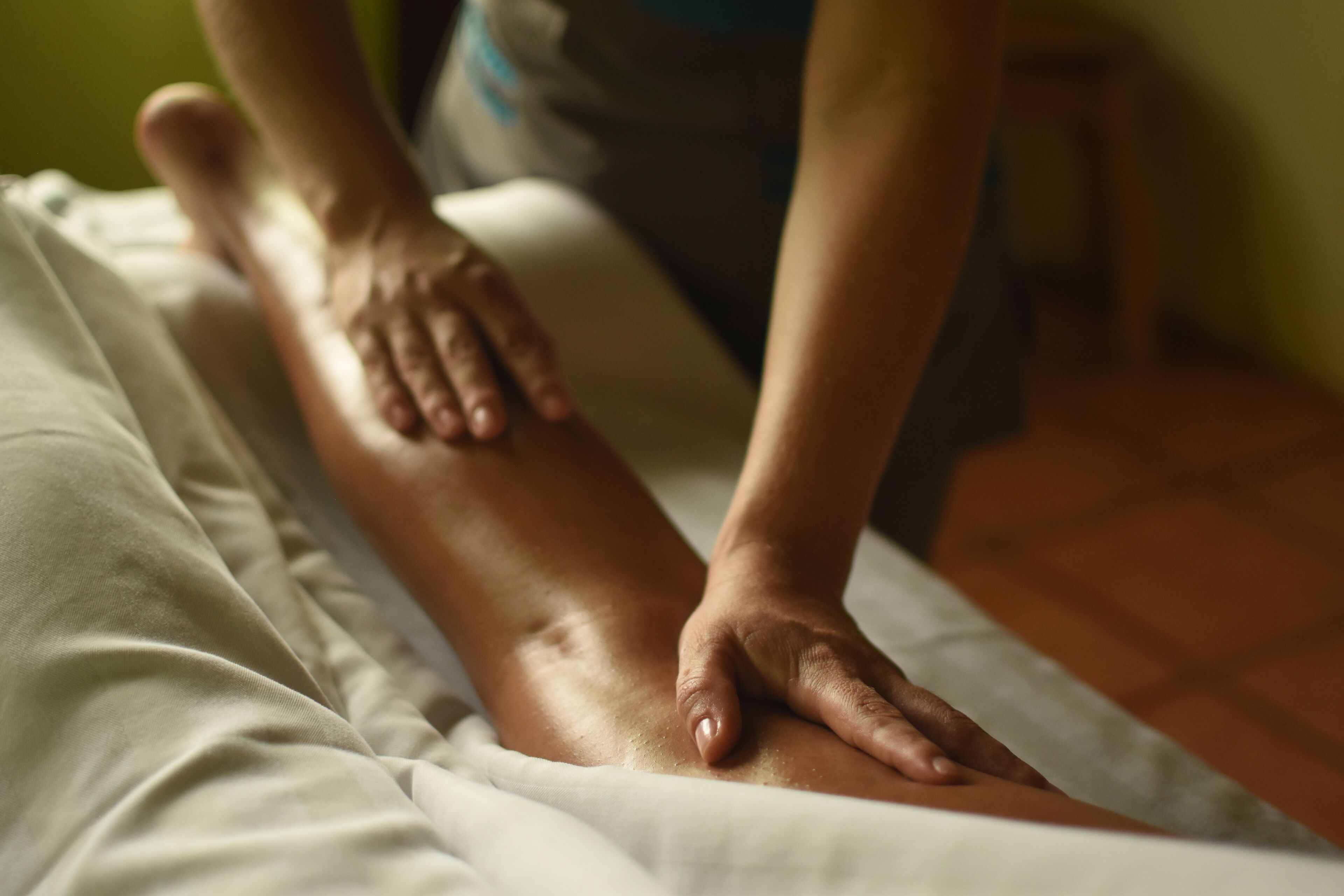 A massage therapy session in progress on a bed with a white sheet.