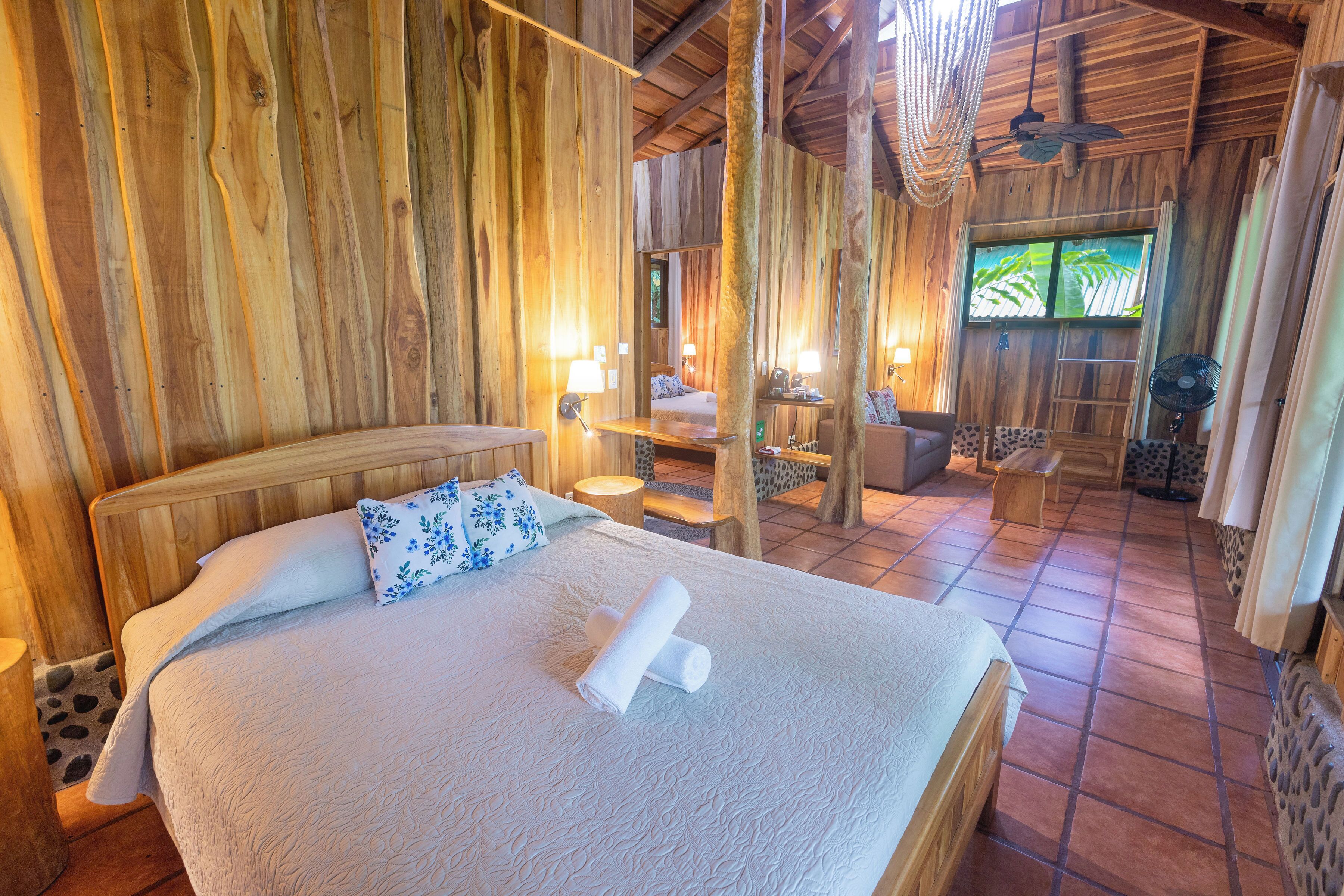 A wooden room with a bed, a fan, and a window.