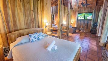 A wooden room with a bed, a fan, and a window.
