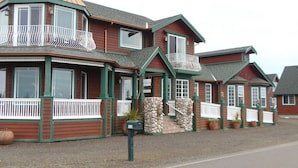 Ein zweistöckiges Gebäude mit grünen und braunen Fassade, mehreren Balkonen und einer Steinverkleidung.