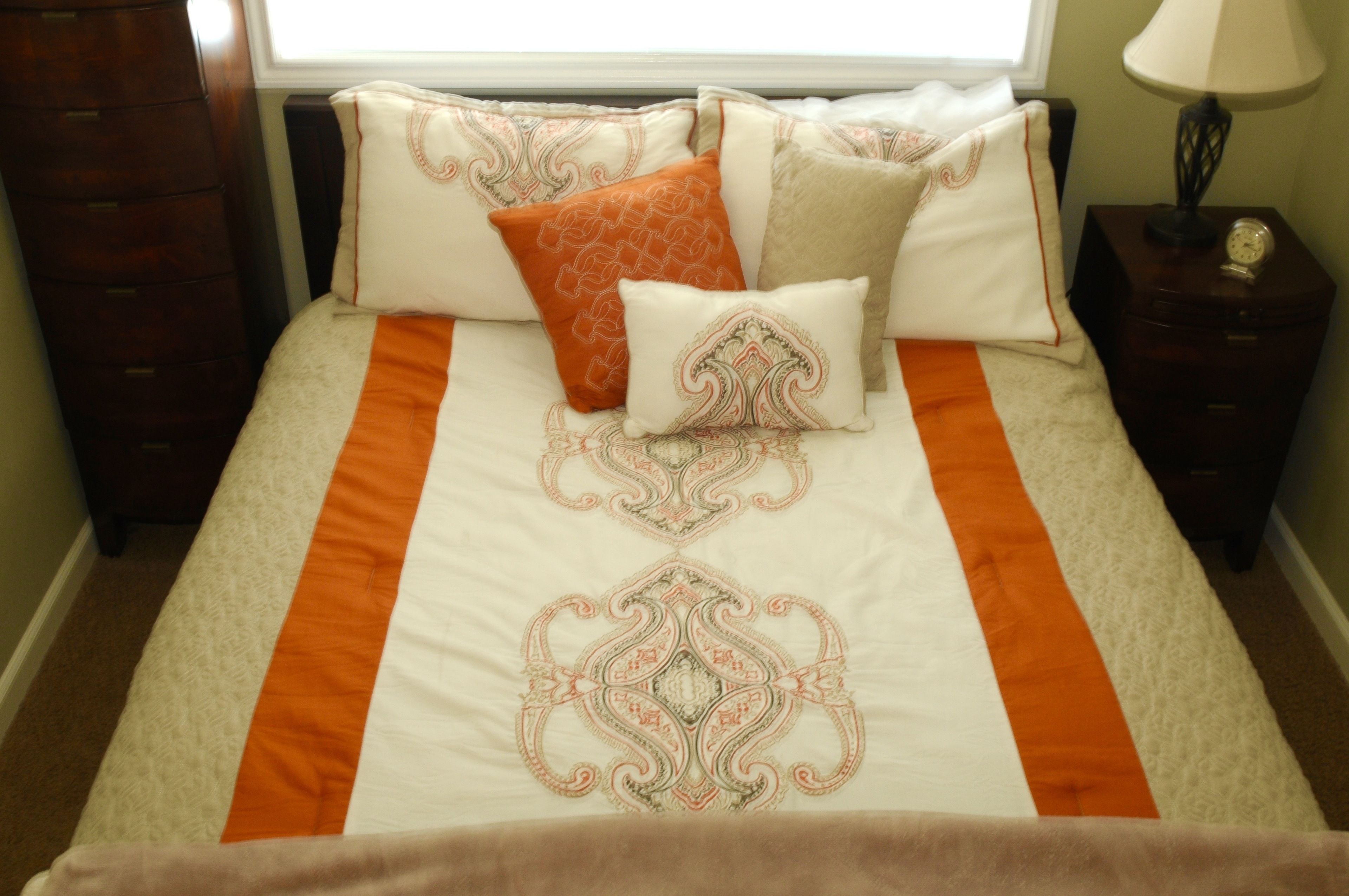 Una cama con un edredón estampado y varias almohadas.