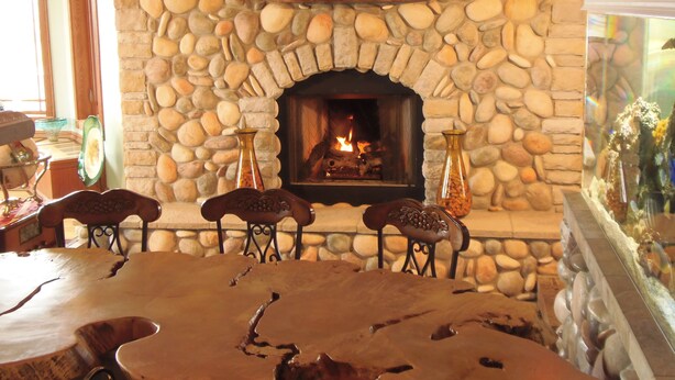 Ein Steinkamin mit Feuer, umgeben von einer rustikalen Steinmauer.