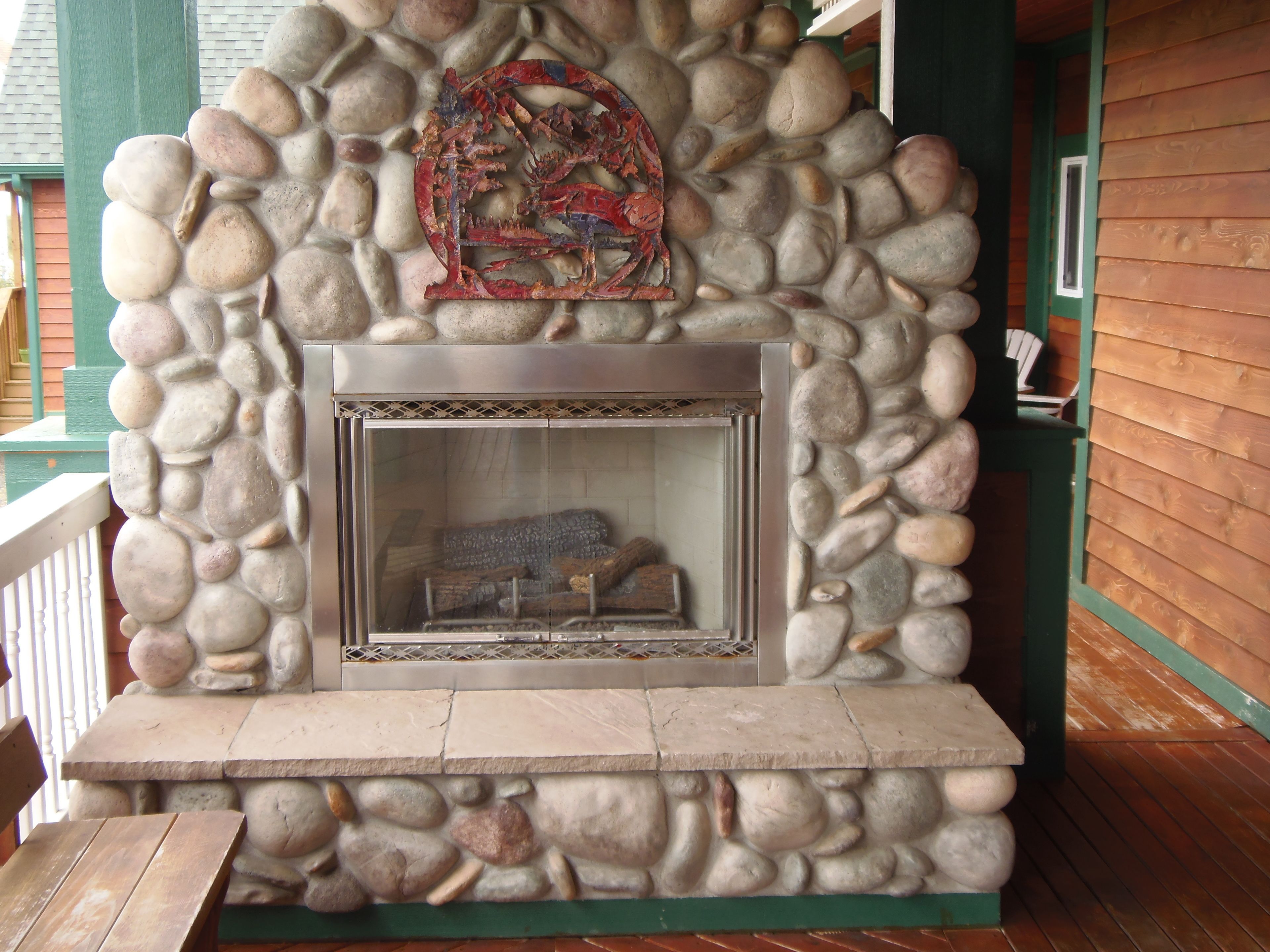 A stone fireplace with a metal grate, surrounded by a stone wall.