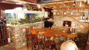 Eine Bar mit Steinwand, Holzbalken und einem großen Aquarium.
