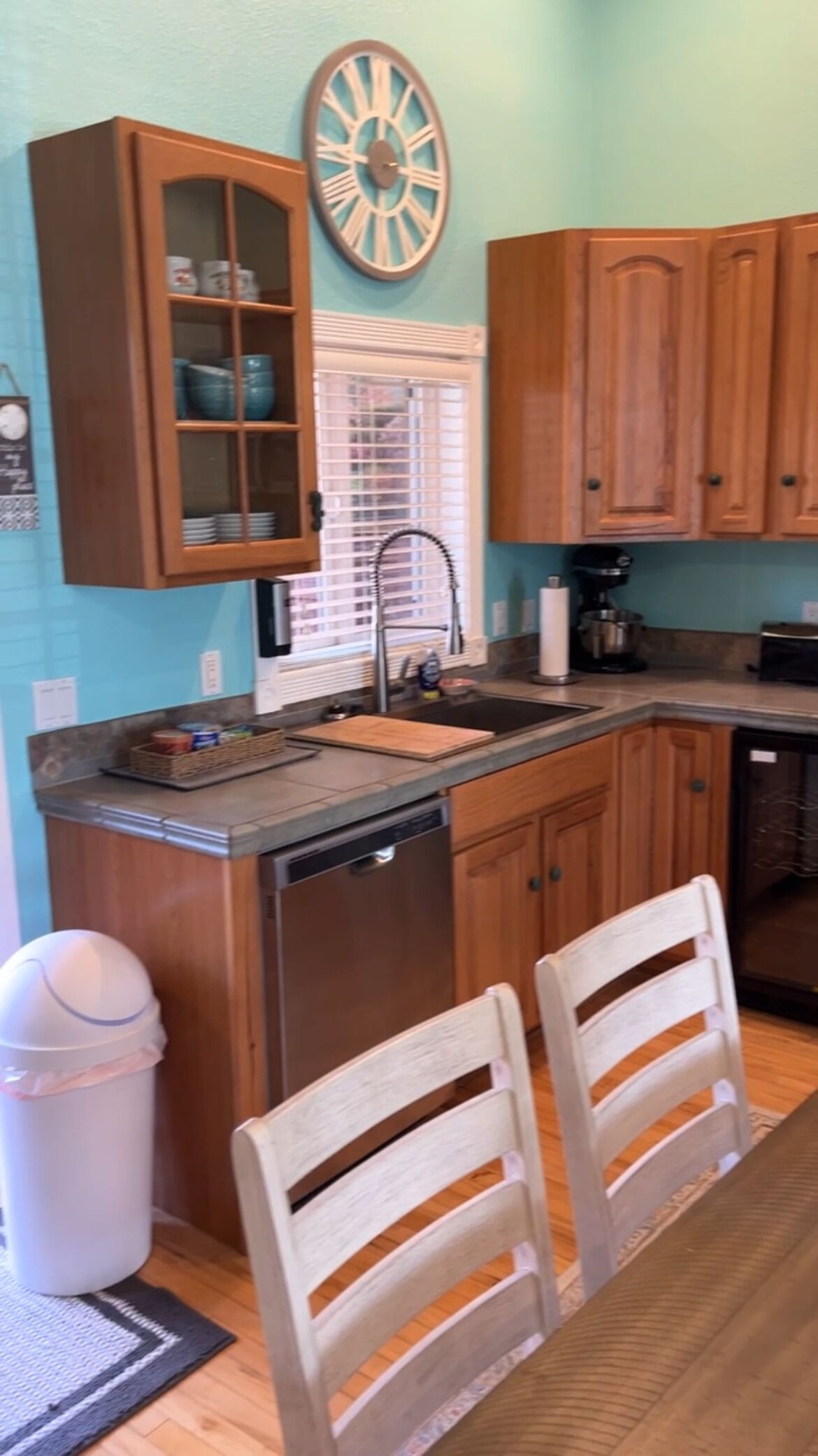 Una cocina con armarios de madera, un lavamanos y una zona de comedor con dos sillas.