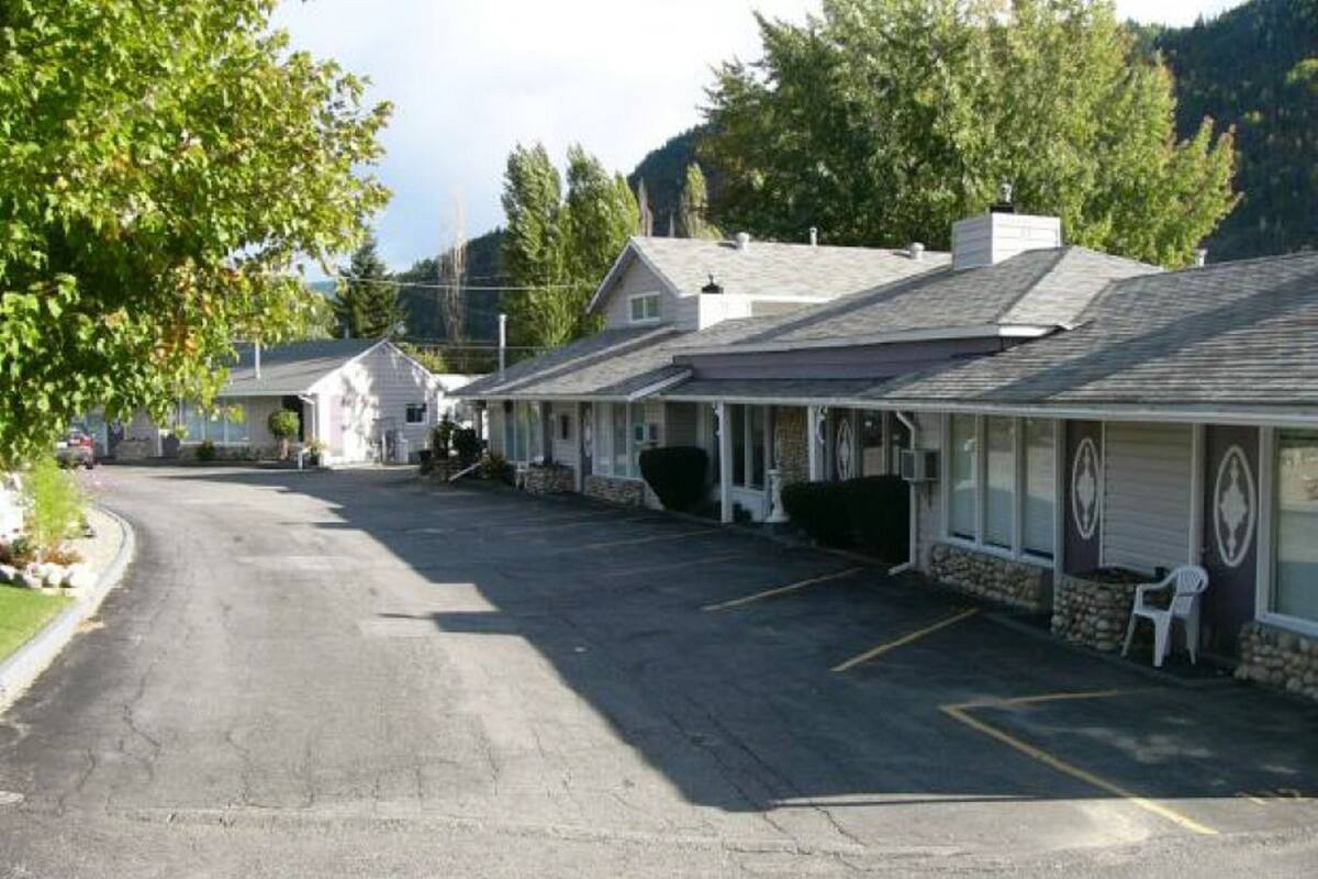 A row of motel-style buildings with a parking lot in front.