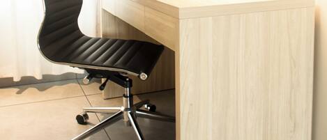 Un bureau moderne avec une chaise de bureau noire, une lampe et une plante en pot.