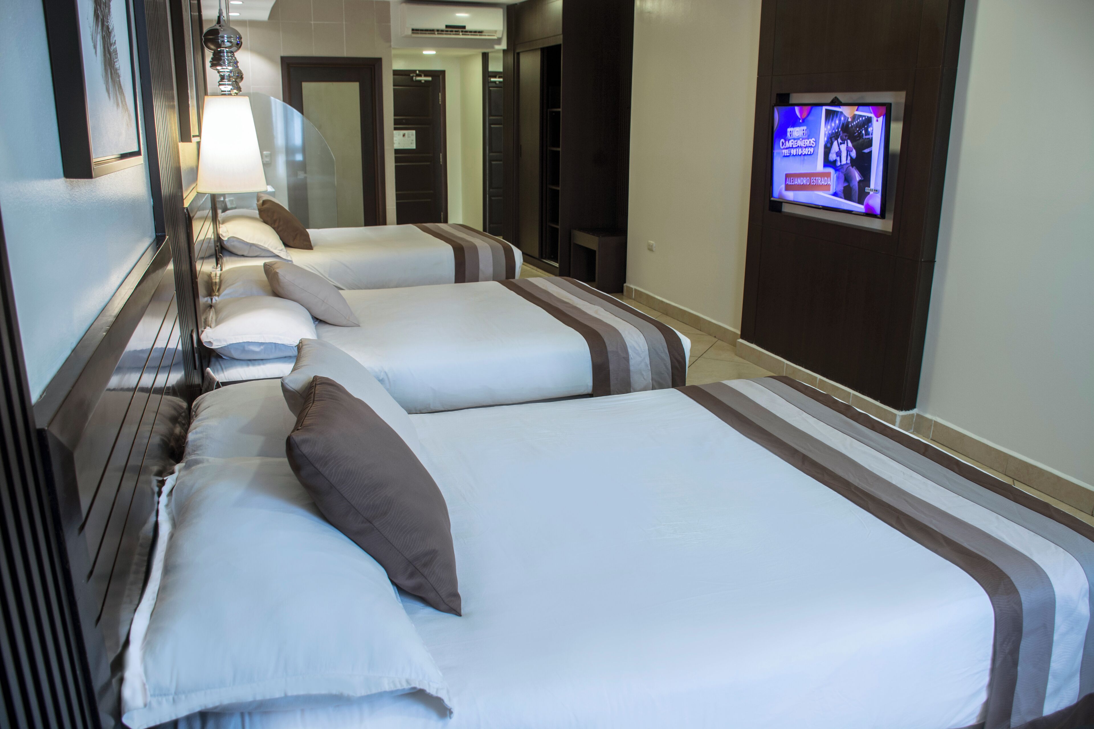 A hotel room with two beds, a TV mounted on the wall, and a mirror.