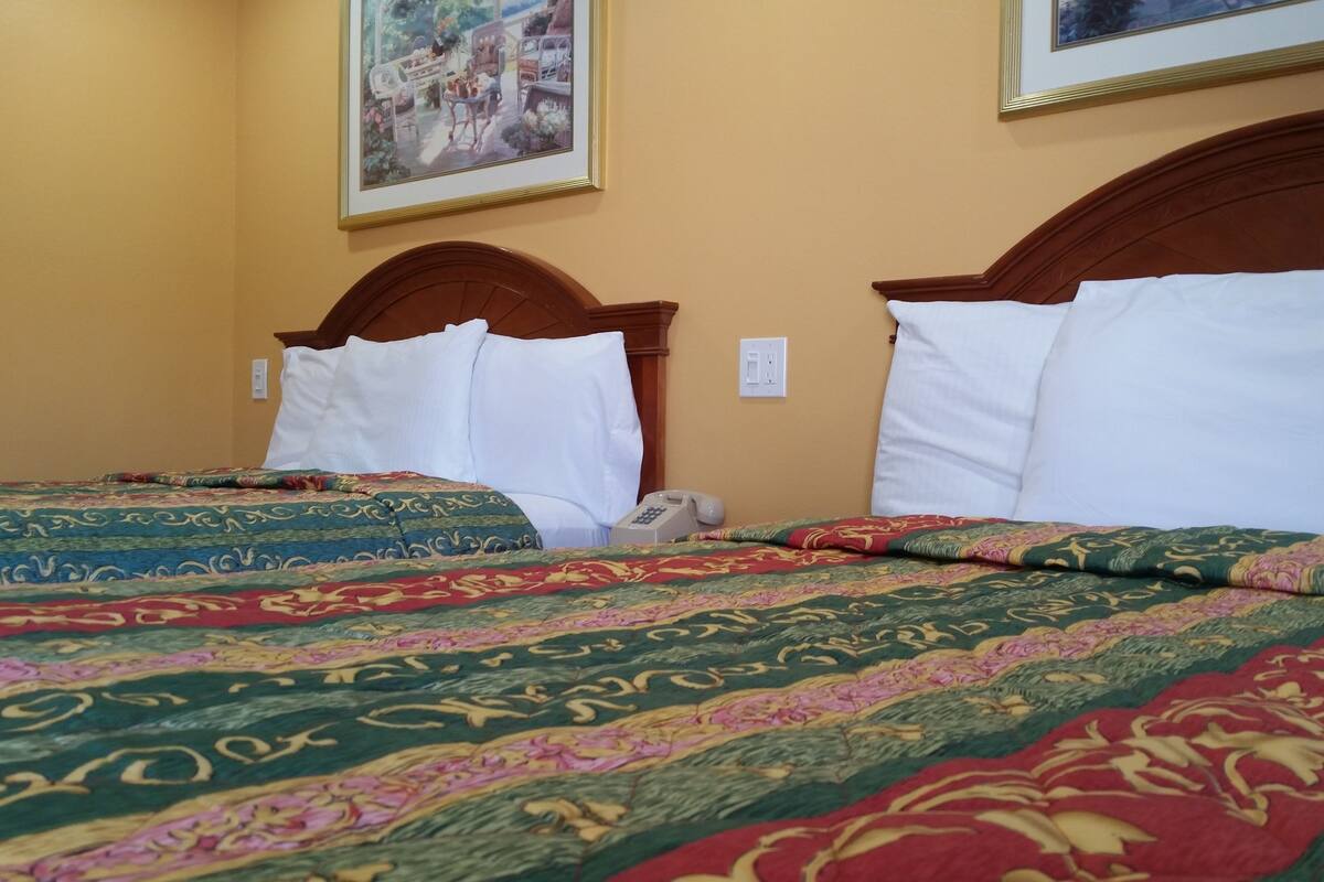 Une chambre d’hôtel avec deux lits, chacun doté d’une tête de lit en bois et de linge de lit blanc. Il y a un téléphone sur la table de chevet.