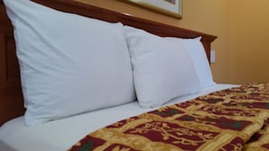 Un lit avec des oreillers blancs et une couvre-lit à motifs.