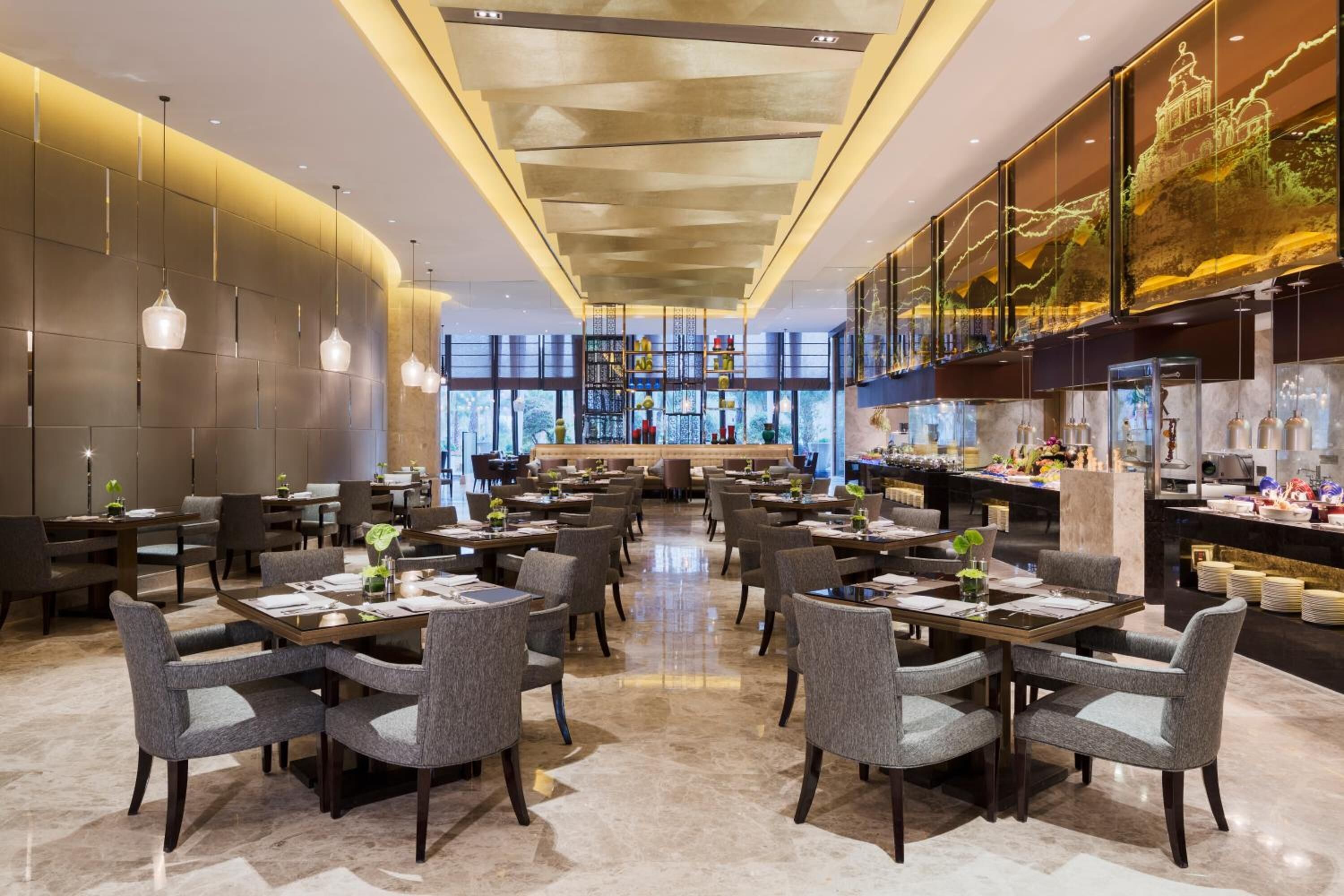 Un restaurante moderno con una barra central, varias mesas de comedor con sillas y grandes ventanales que permiten la entrada de luz natural.