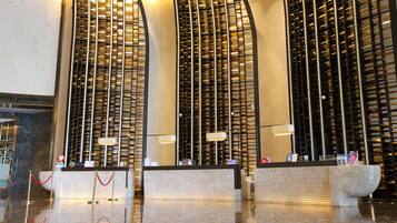 Un hall d’hôtel moderne avec un comptoir d’accueil, une grande sculpture abstraite et un mur orné d’un motif en forme de quadrillage.