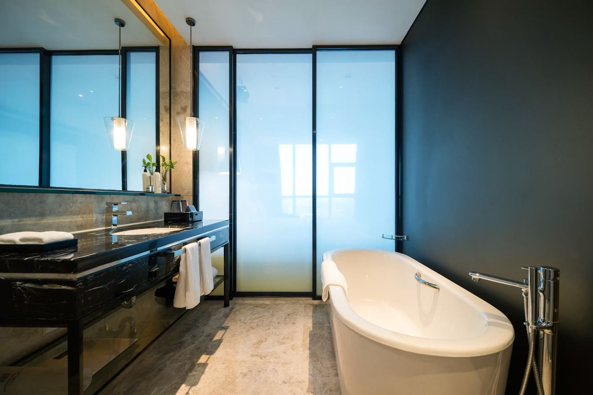 A modern bathroom with a large bathtub, a vanity with a mirror, and a large window.