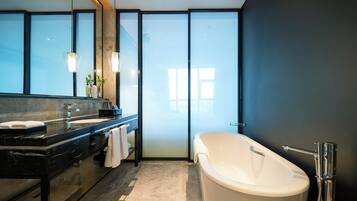 Une salle de bain moderne avec une grande baignoire, un meuble-lavabo avec un miroir et une cabine de douche en verre.