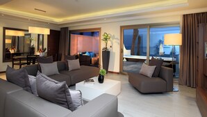 A modern hotel room with a living area featuring sofas, a coffee table, and a dining area with a table and chairs. - Dana Beach Resort (Abqaiq)