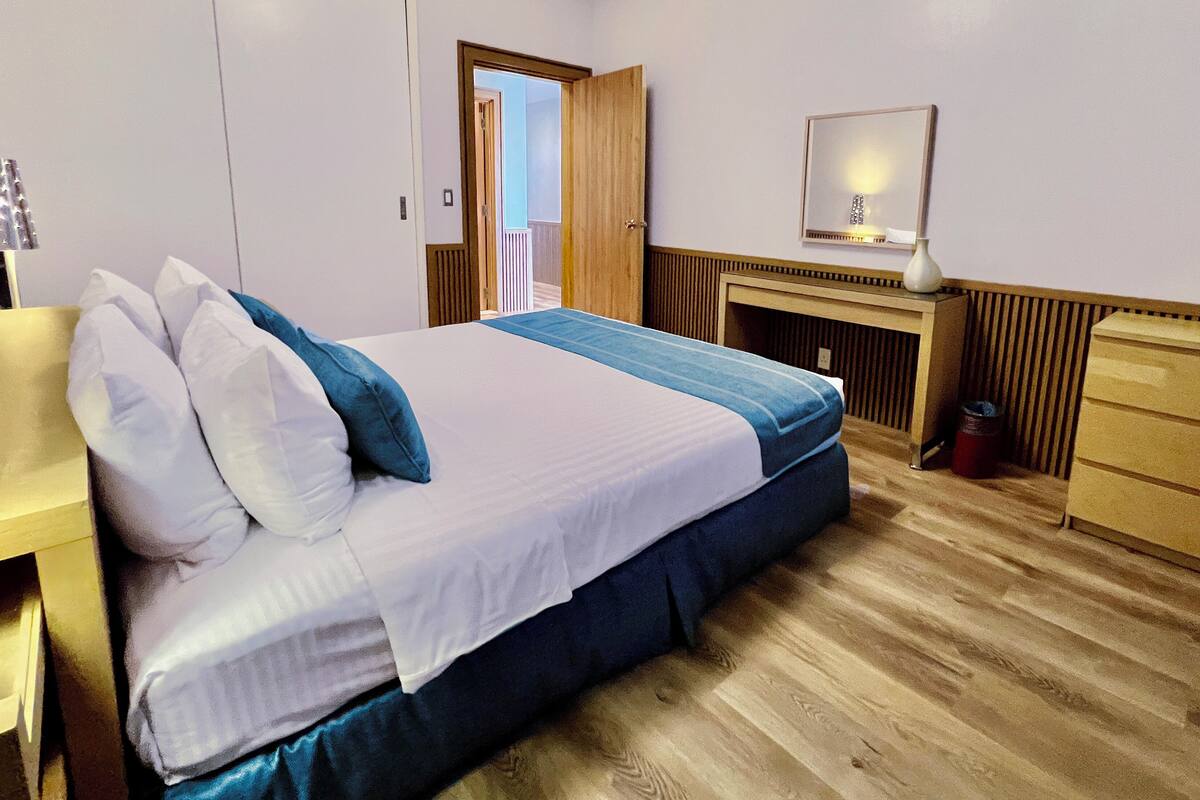 A neatly arranged hotel room with a bed, bedside table, and a mirror.