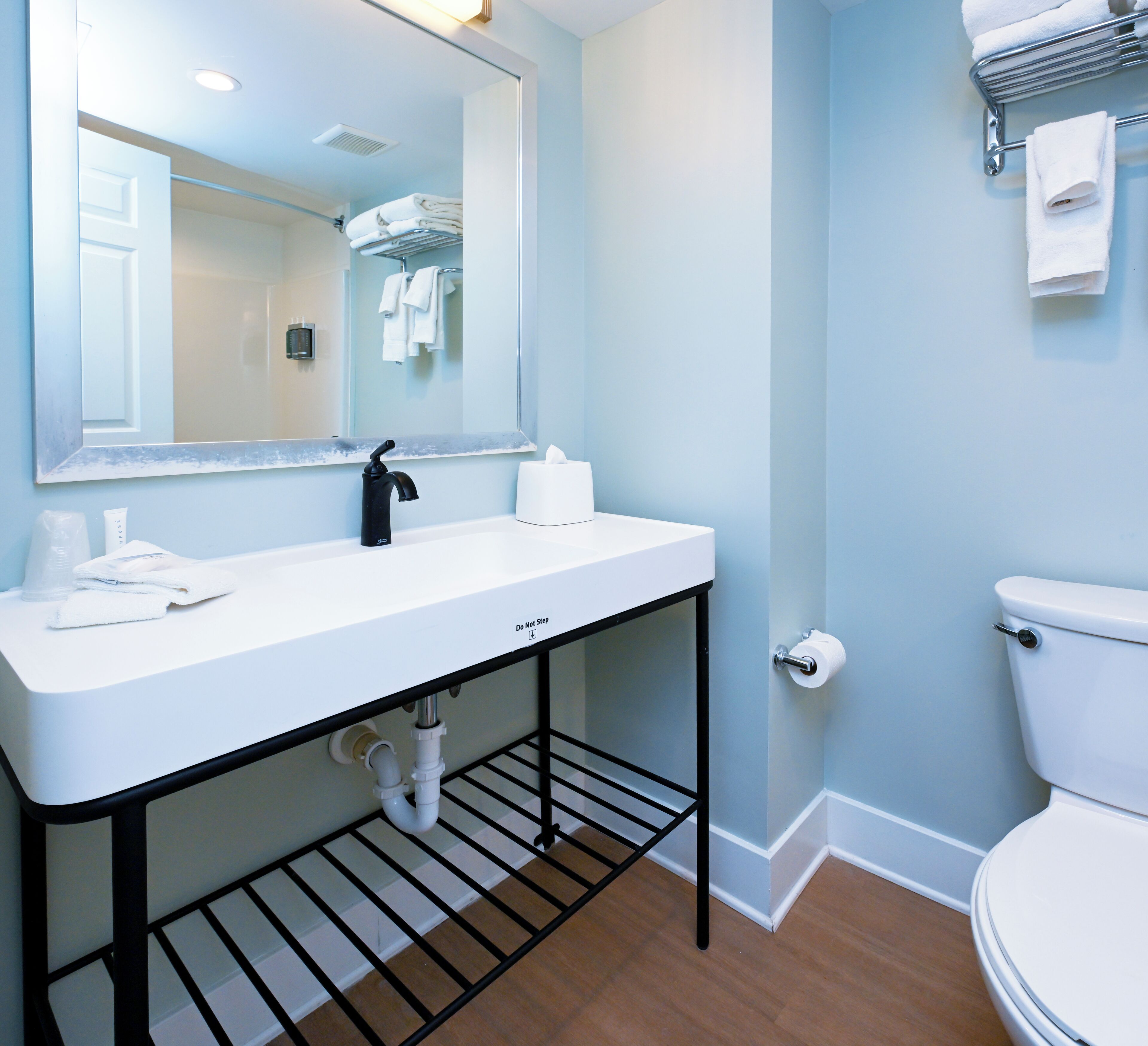 A bathroom with a white sink, black faucet, and a toilet.