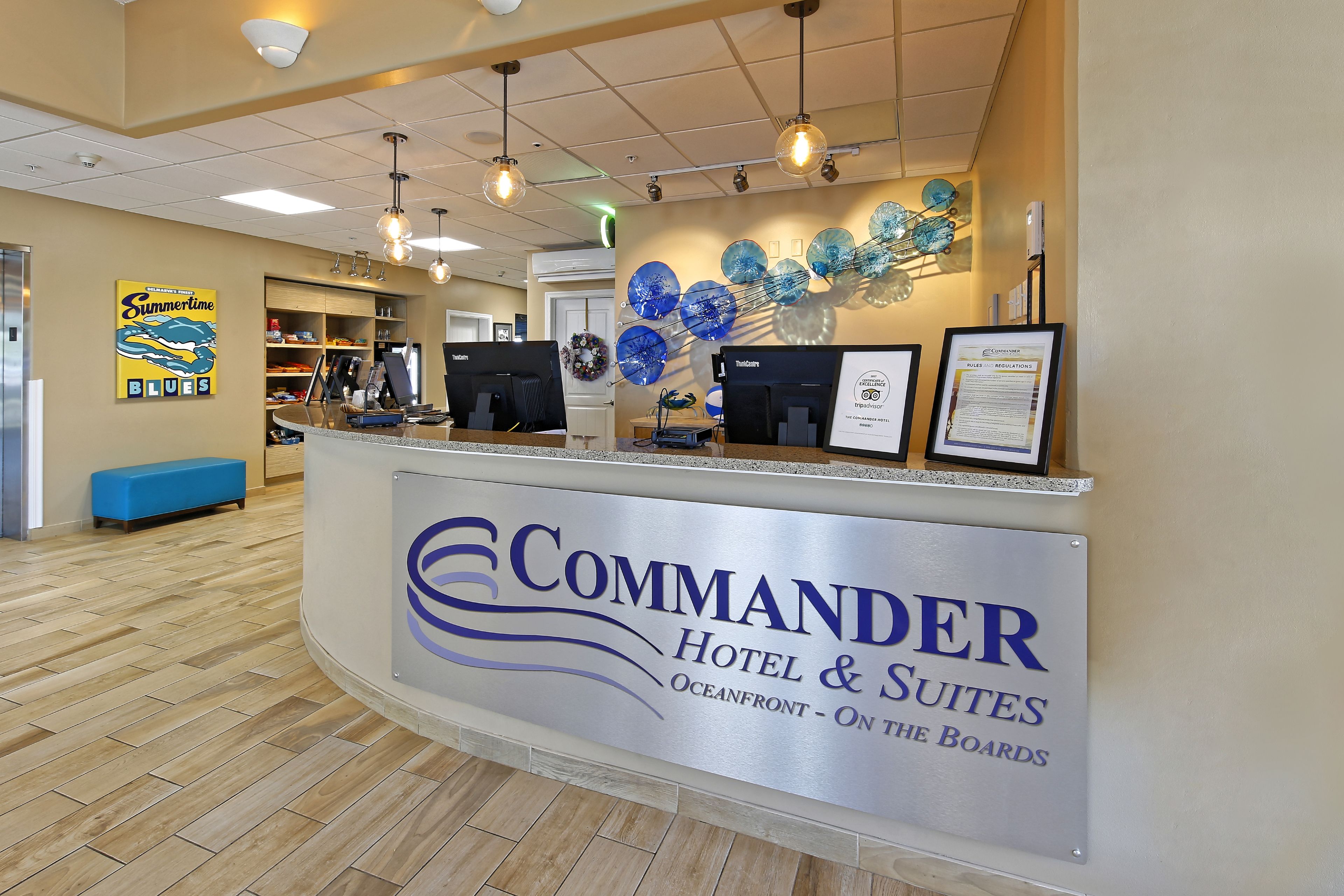 Mostrador de recepción de hotel con un cartel que dice 'COMMANDER Hotel & Suites Oceanfront - On the Boards'.