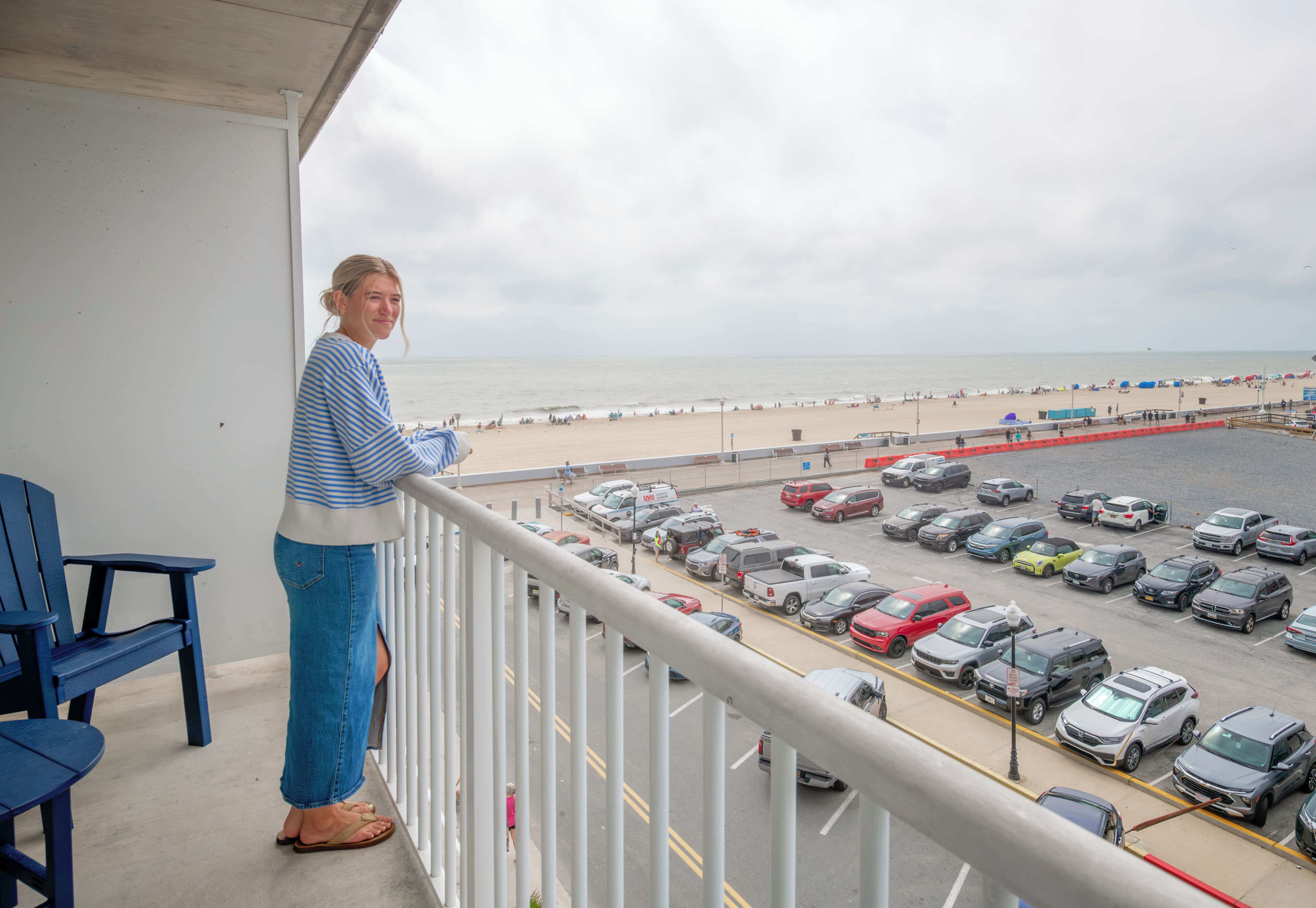 Un balcon avec vue sur une plage et un parking.