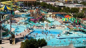 Un parc aquatique doté de nombreux toboggans et de plusieurs piscines, entouré de zones de plage et agrémenté de parasols.
