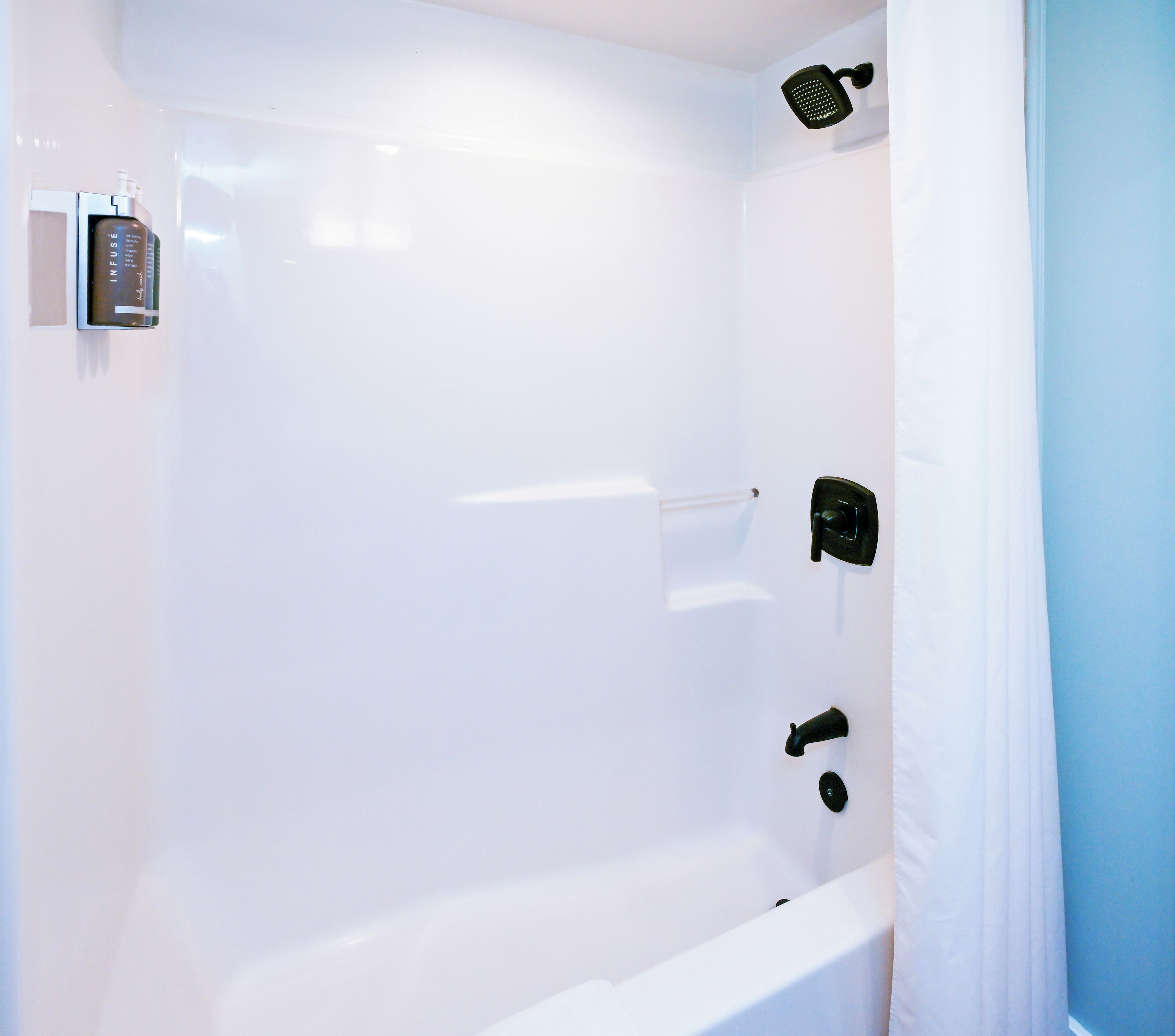 A modern bathroom with a white bathtub, a handheld showerhead, and a wall-mounted faucet.