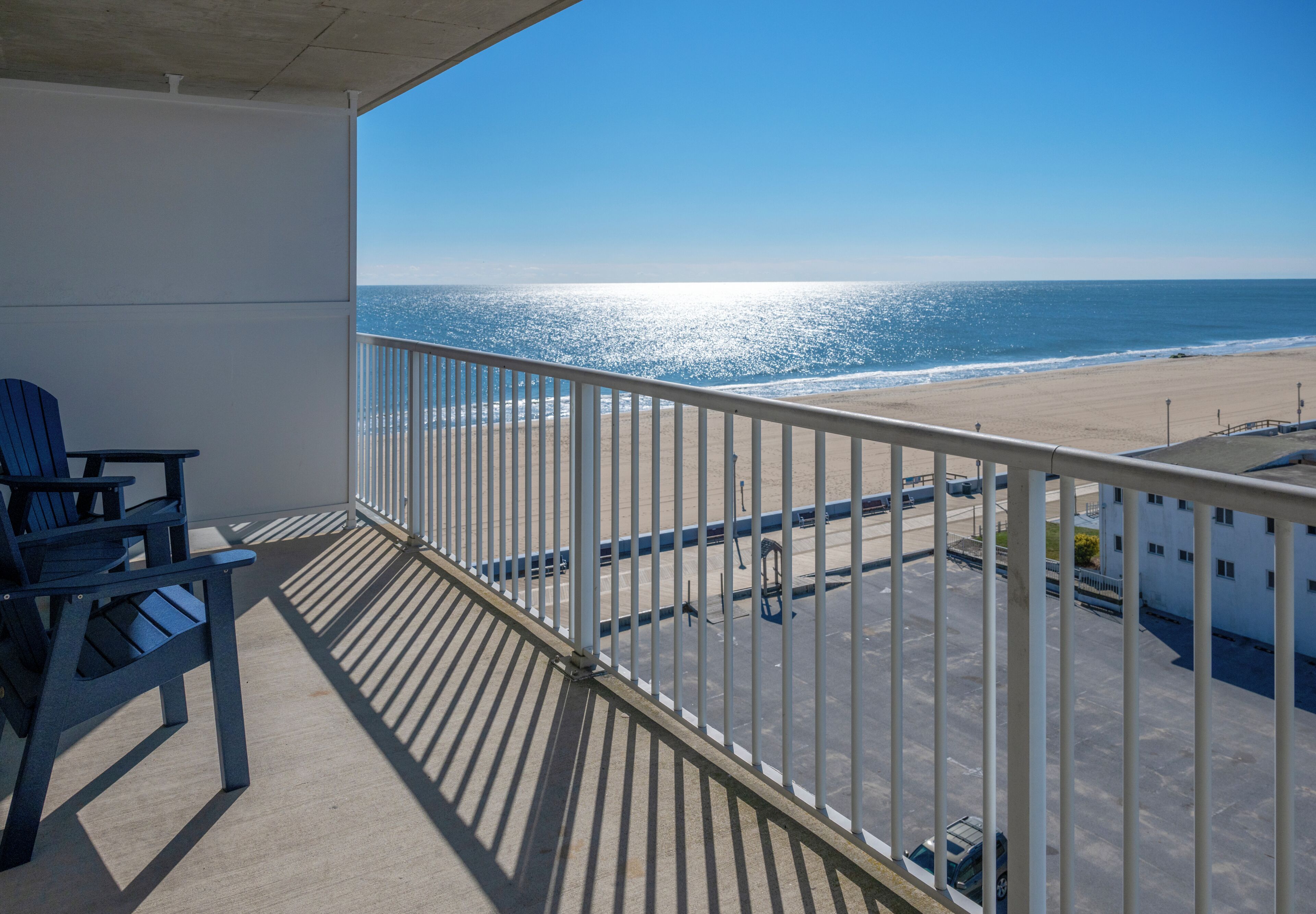 Un balcon donnant sur la plage, une chaise et une rambarde.