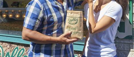 A man and a woman standing in front of a store named "Doll's Popcorn."