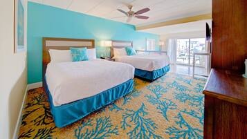 A hotel room with two beds, a ceiling fan, and a view of the city through large windows.