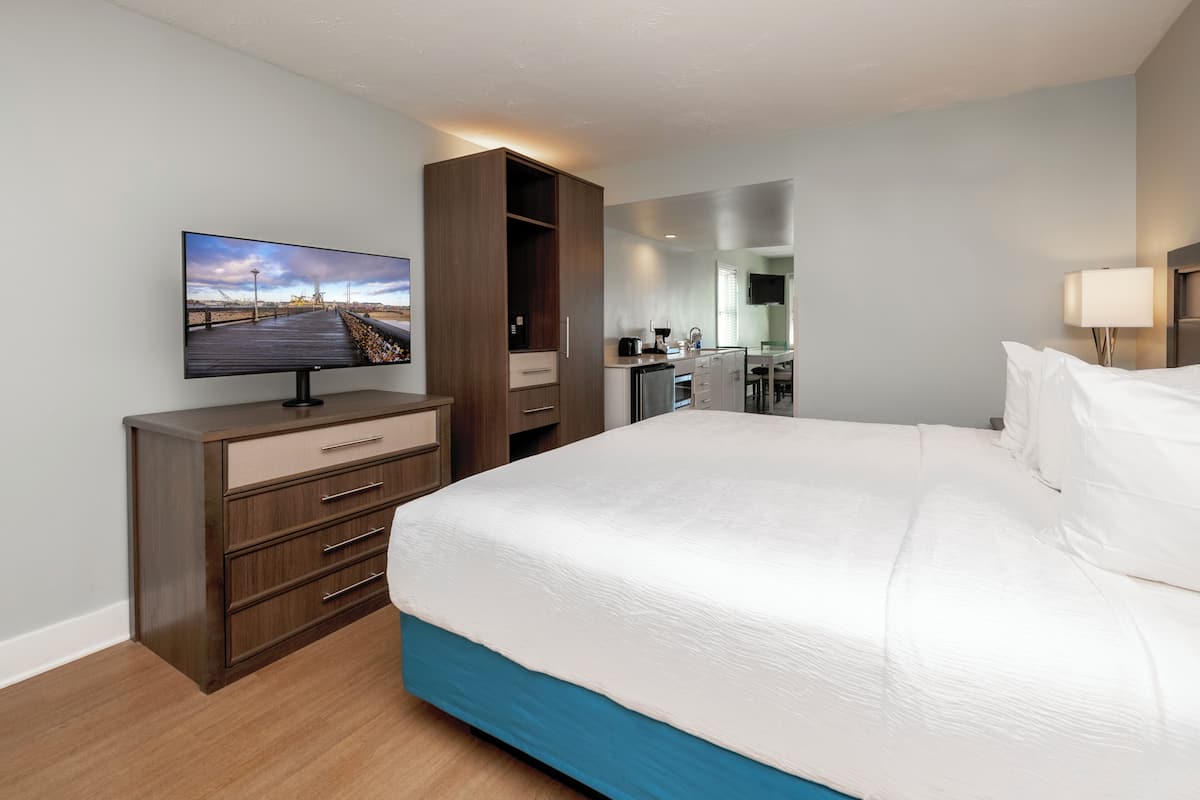 Una habitación de hotel con cama, televisión, escritorio y kitchenette.