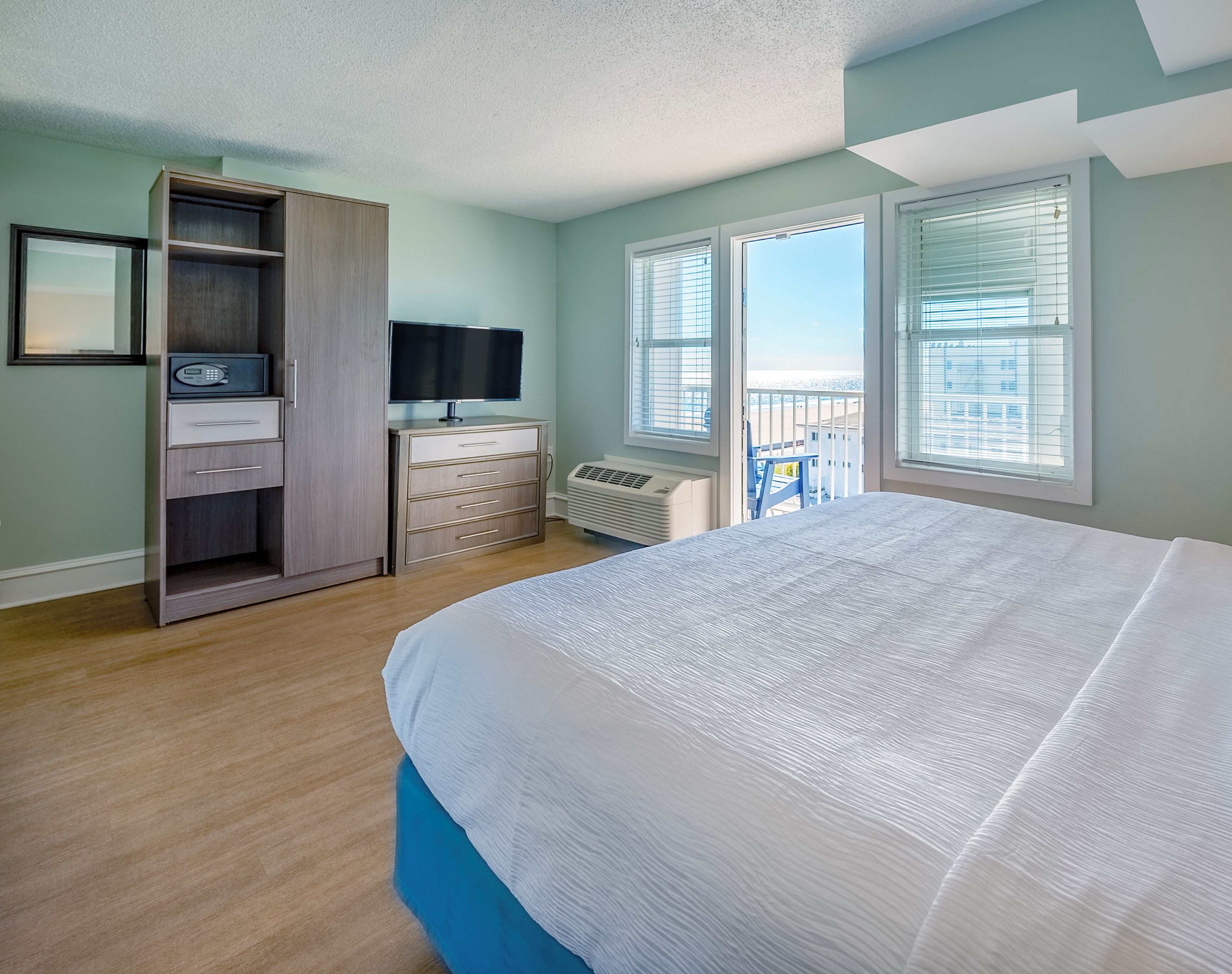 A bedroom with a bed, a wardrobe, a television, and a window with a view.