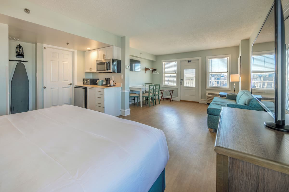 Un espacio habitable compacto con cama, kitchenette, comedor y zona de estar.
