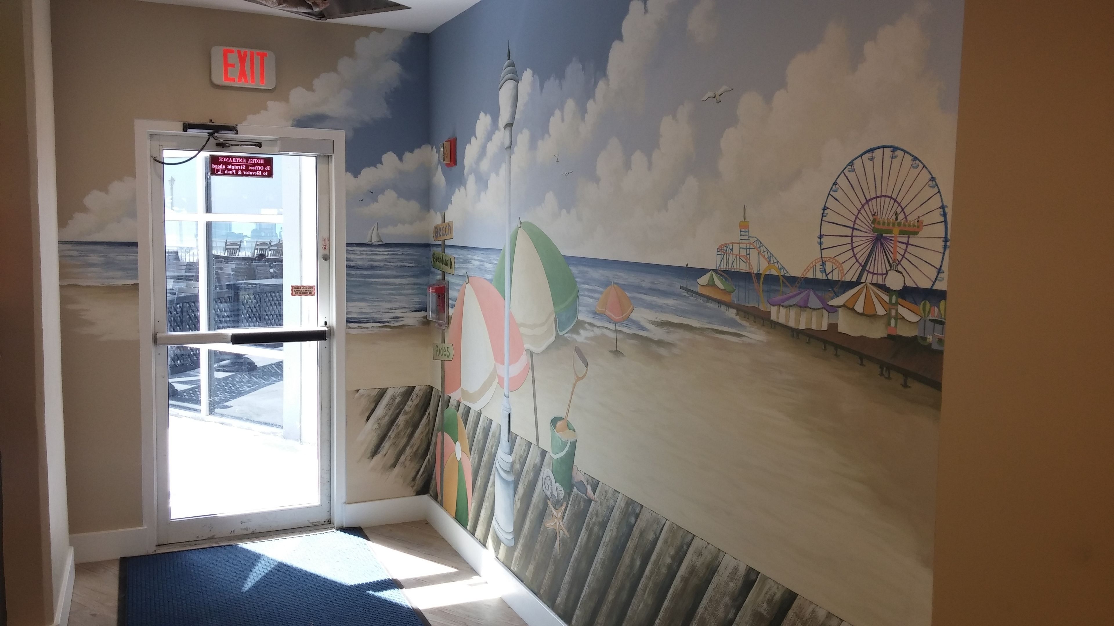 Un mural con temática de playa, que muestra una noria, sombrillas y un muelle.