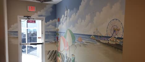 Un mural con temática de playa, que muestra una noria, sombrillas y un muelle.