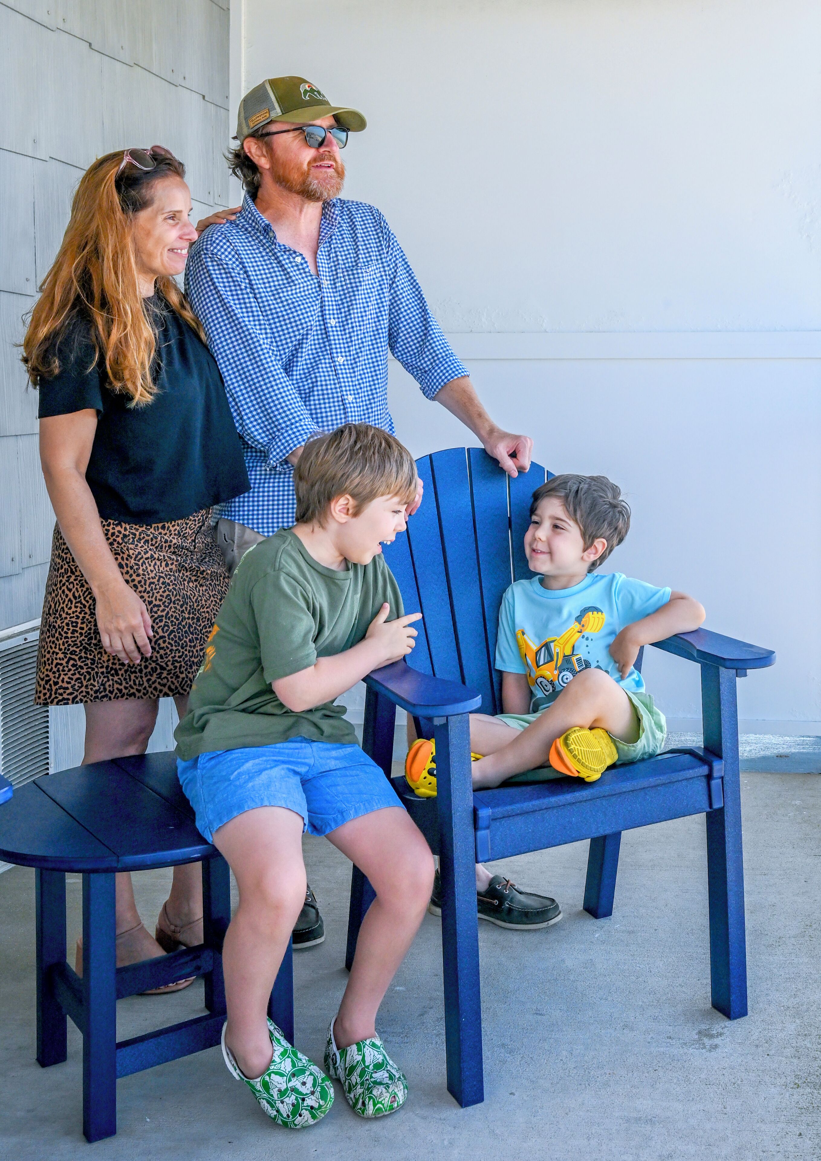 Une famille de quatre personnes assise sur une chaise bleue, à l’extérieur.