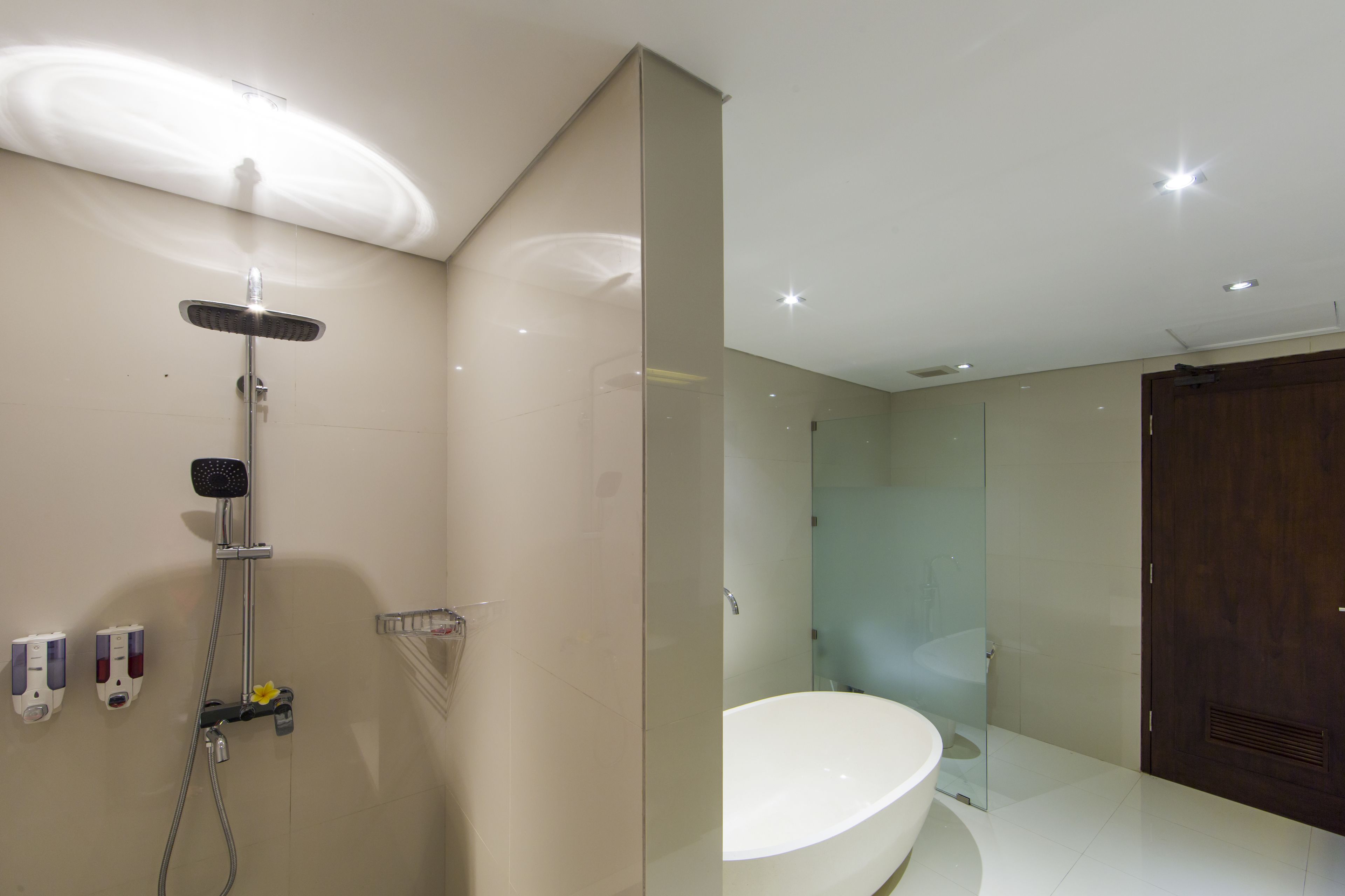 Un baño moderno con cabina de ducha de vidrio, bañera blanca y puerta de madera.