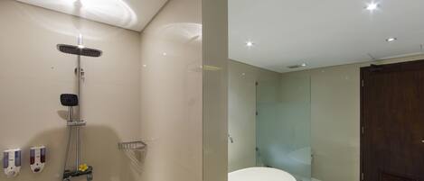 Un baño moderno con cabina de ducha de vidrio, bañera blanca y puerta de madera.