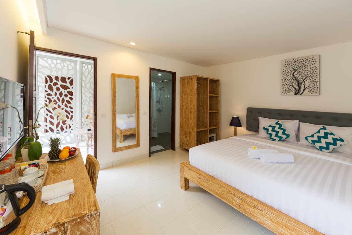 Ein modernes Hotelzimmer mit einem großen Bett, einem Holz-Kopfteil und einem Essbereich mit einem Holztisch und Stühlen.
