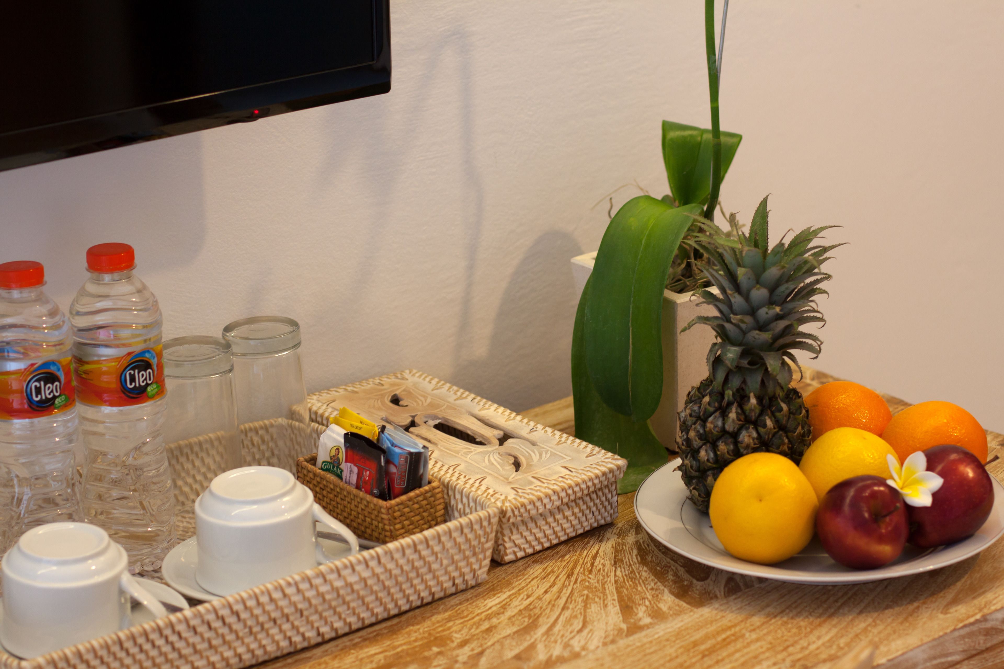 A breakfast setup with a plate of fruit, a pineapple, and a bottle of Cleo water.