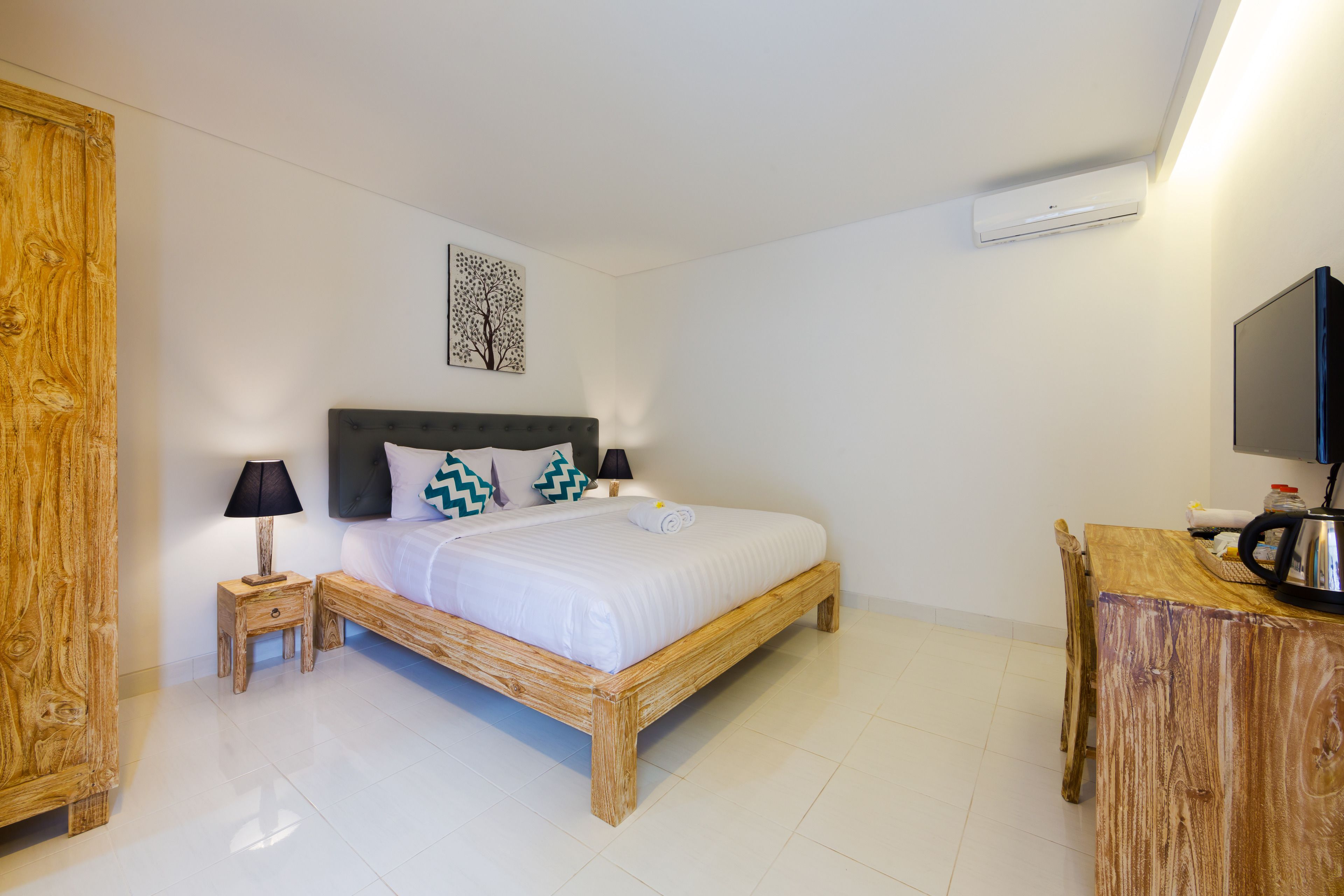 A bedroom with a wooden bed, bedside tables, a TV, and a wall-mounted air conditioner.