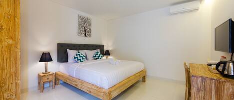A bedroom with a wooden bed, bedside tables, a TV, and a wall-mounted air conditioner.