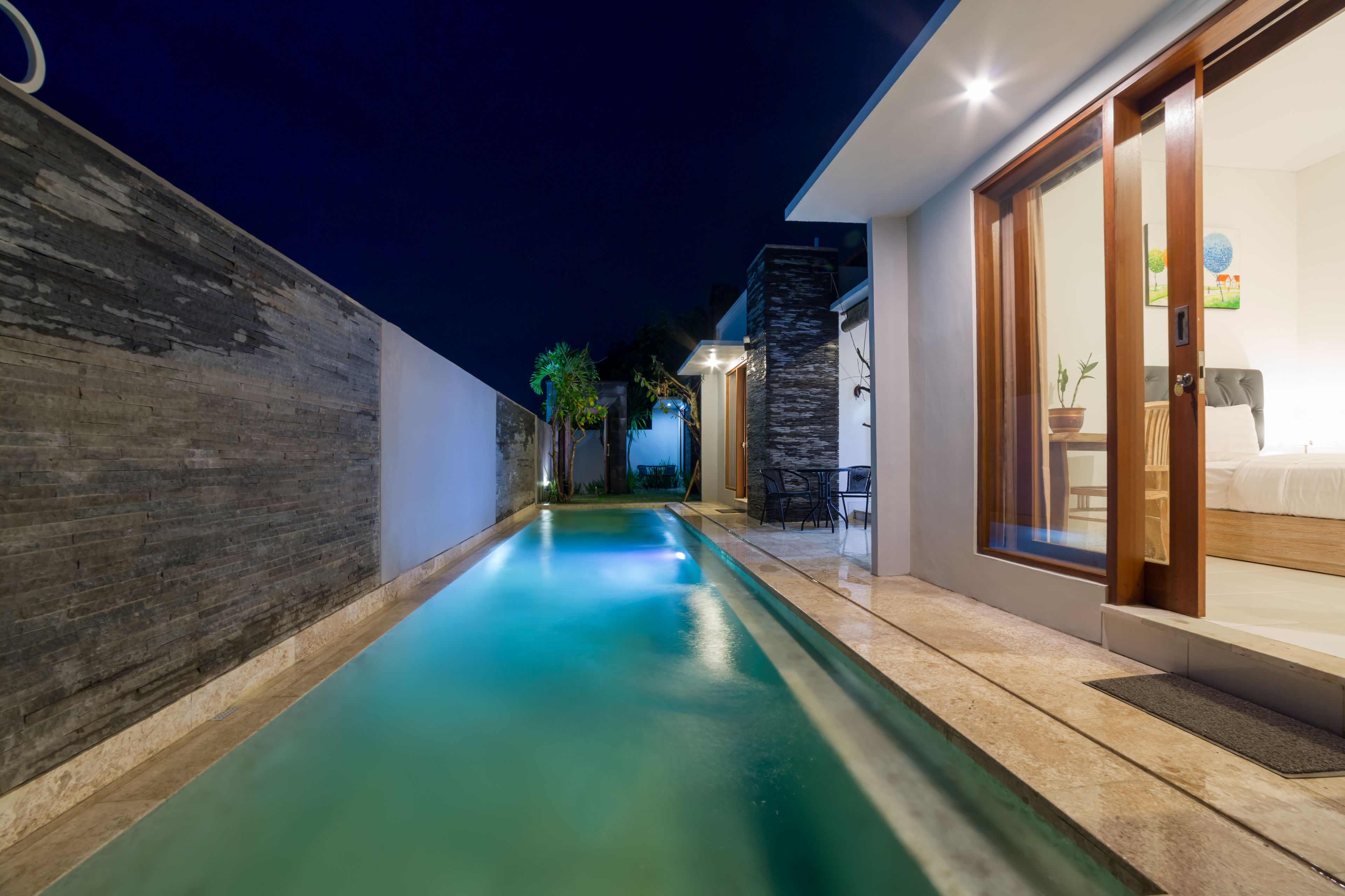 A modern house with a swimming pool, a wooden deck, and a bedroom with a large window.