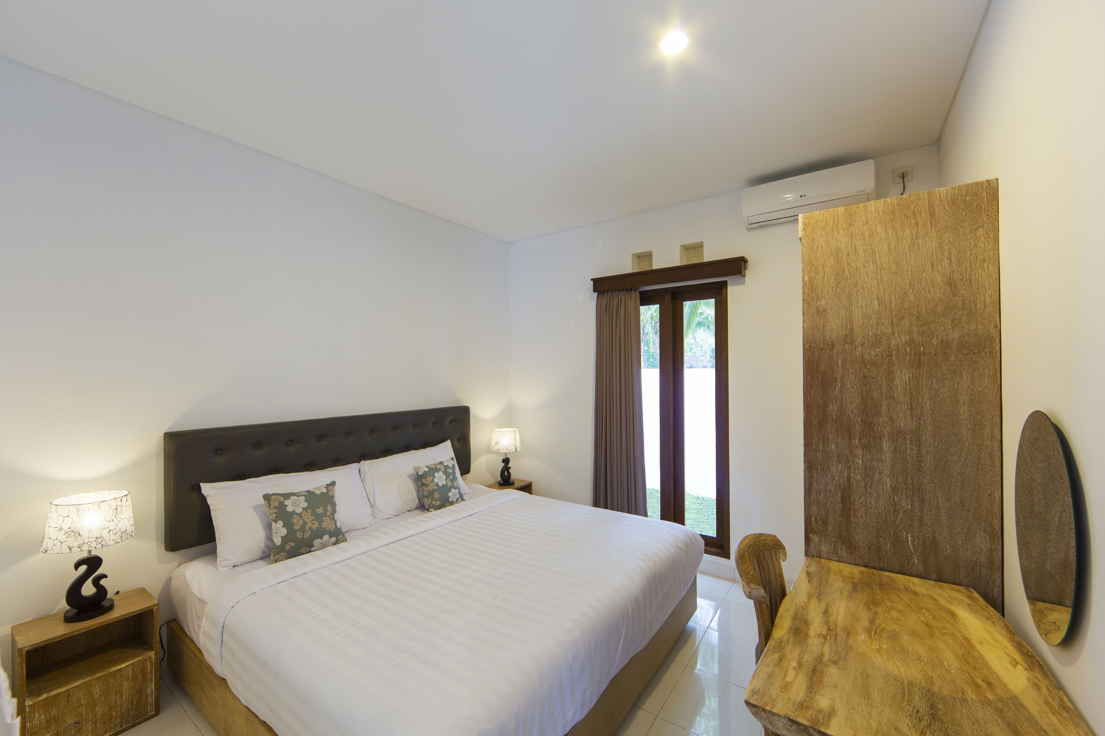 Une chambre à coucher avec un grand lit, une table de chevet avec une lampe, une table en bois et un miroir.